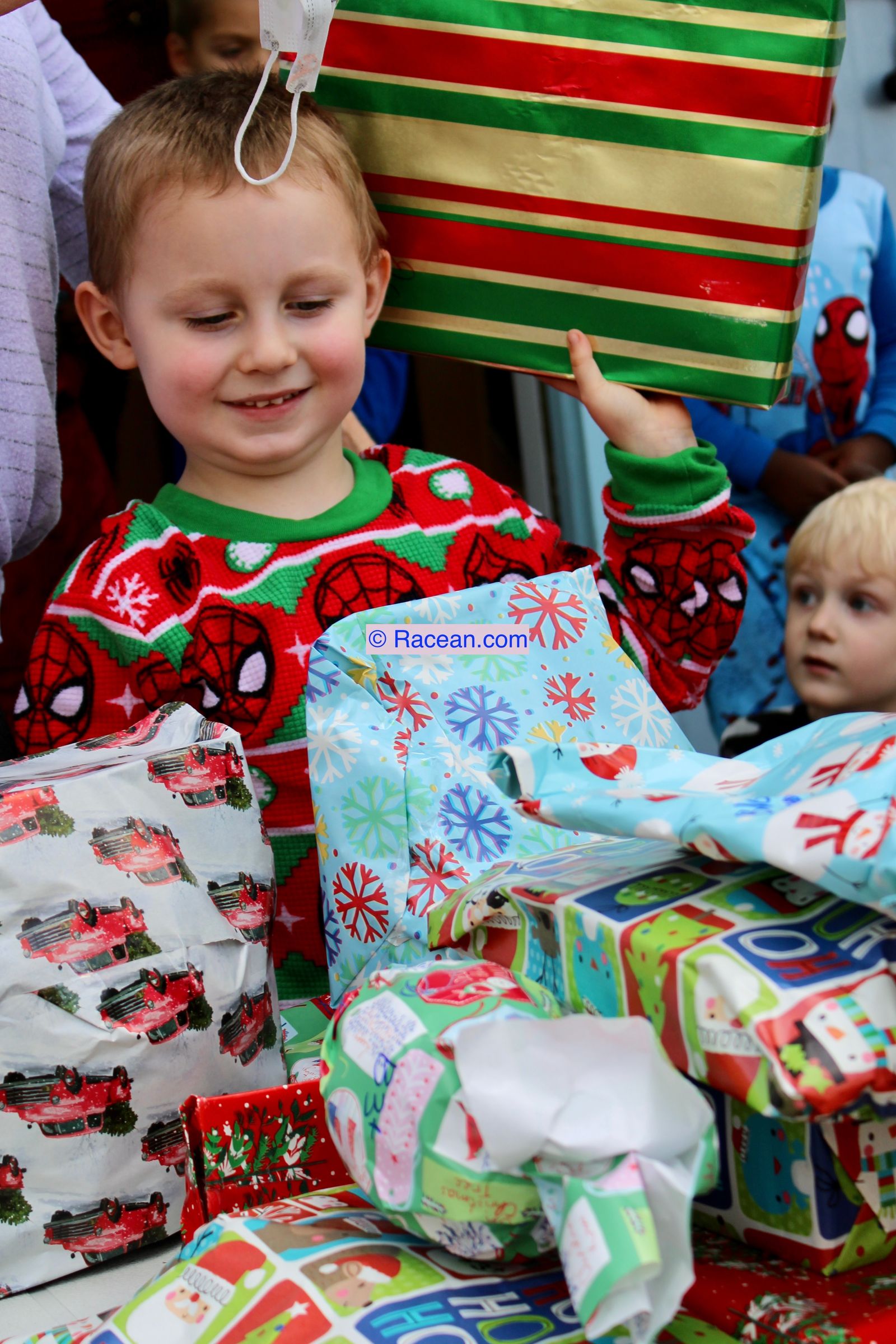 A boy in a Christmas sweater with gifts